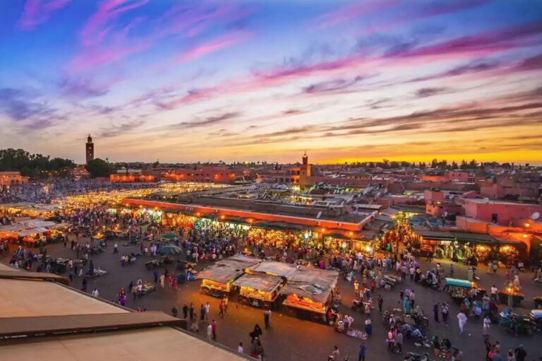 Nighttime view of Jemaa el Fna square in Marrakech, showcasing a lively open-air market with food stalls, traditional Moroccan dishes, vibrant street performers, and a bustling crowd.