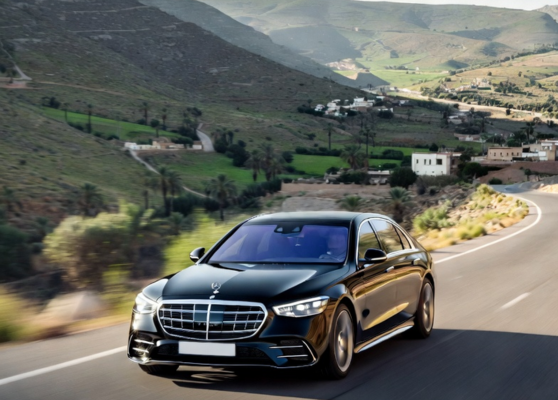Luxury Mercedes S-Class driving through scenic Moroccan landscapes between Marrakech and Tangier